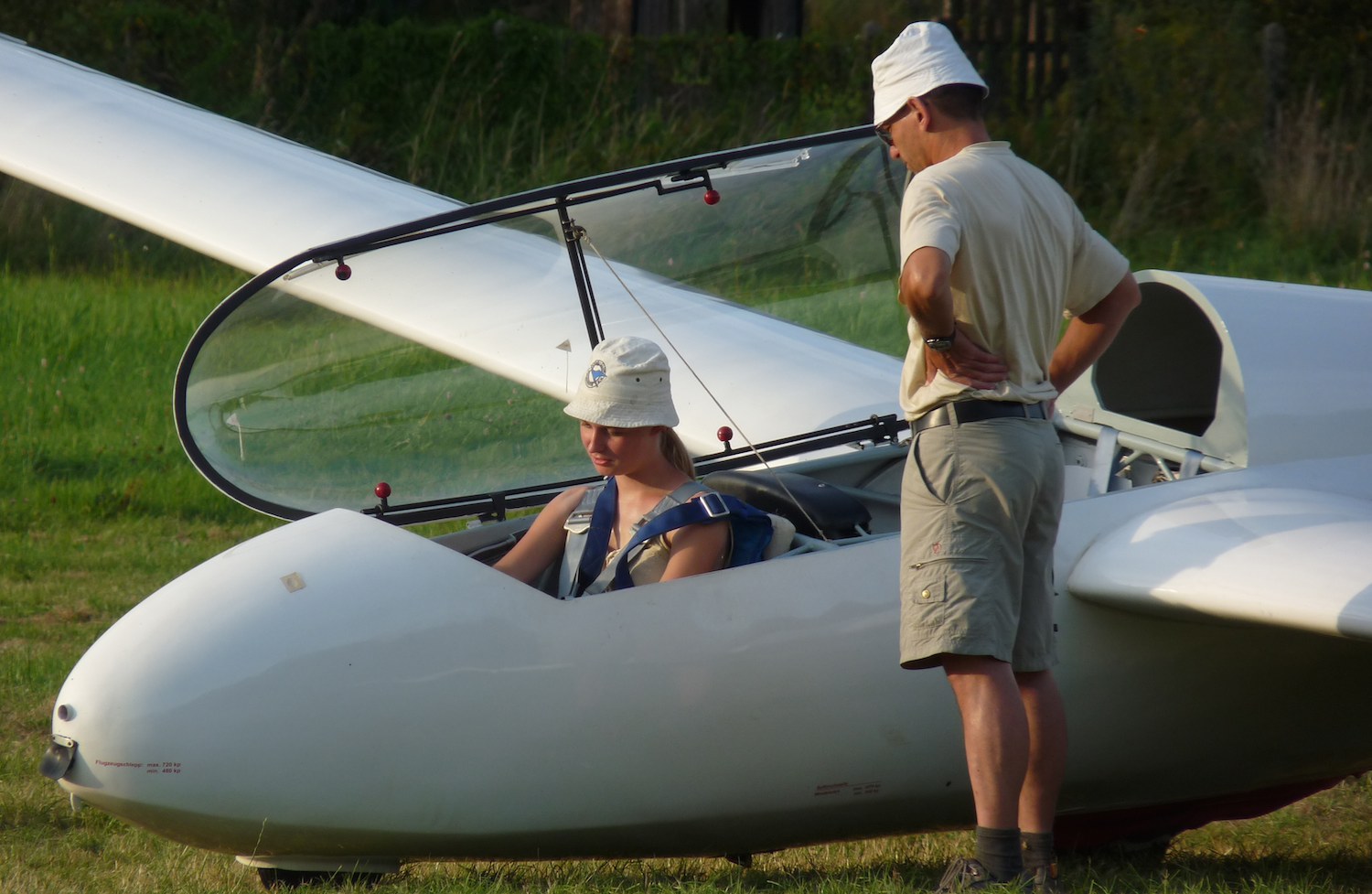 Fluglehrer bespricht sich mit einer Flugschülerin im Cockpit eines Segelflugzeugs